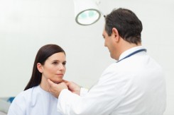 Doctor auscultating the neck of his patient in an examination room